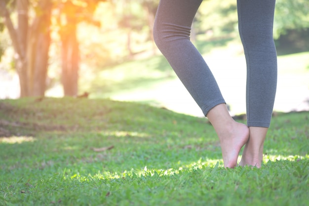 Fille debout pieds nus sur l&#39;herbe verte dans le parc