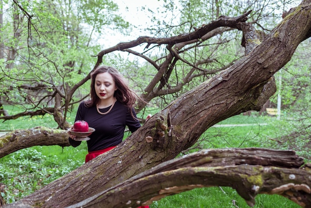 Fille debout près d'un tronc d'arbre