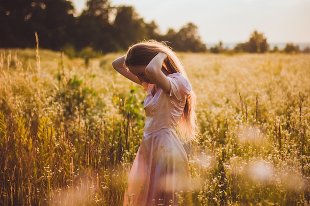 Fille debout sur le terrain dans une robe rose