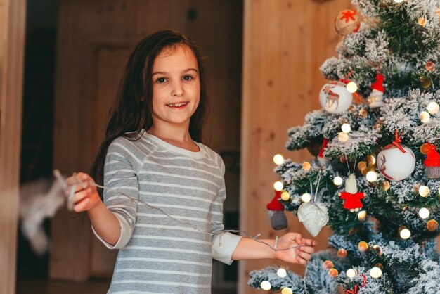 une fille décorant un arbre de Noël à la maison