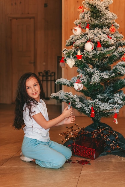 une fille décorant un arbre de Noël à la maison