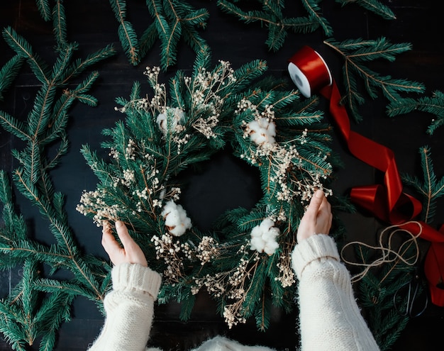 Fille décore la guirlande de Noël elle-même sur la table à la maison