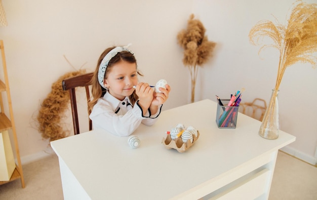 Une fille décore un œuf de PâquesL'enfant dessine au feutre sur un œuf concentré sur la tâche