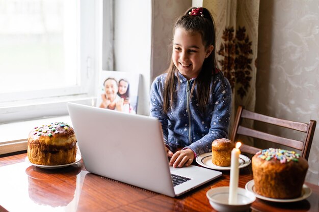 Fille démontrant des œufs et saluant avec les vacances de printemps sa famille via Internet, célébration en ligne Eater, nouvelle distance normale et sociale.