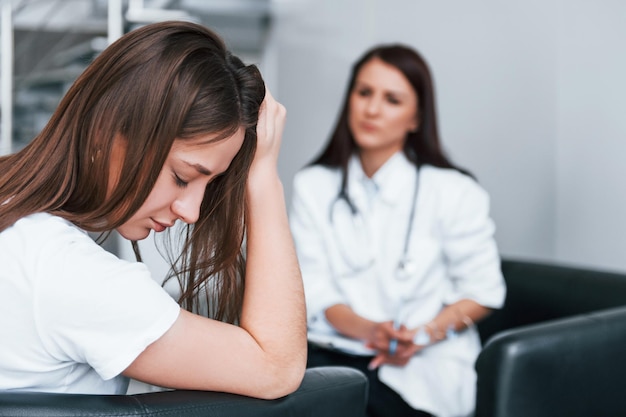 Une fille a une dépression mentale et pleure Une jeune femme rend visite à une femme médecin dans une clinique moderne