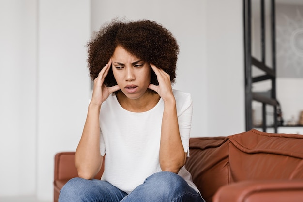 Fille déprimée avec migraine Triste femme afro-américaine touche les tempes à cause du stress et du désespoir dans sa vie Problèmes dans la vie