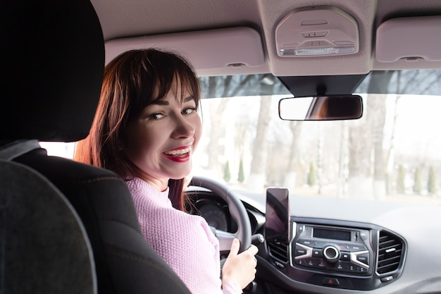 La fille derrière le volant sourit