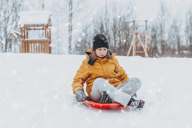 Une fille descend un toboggan dans un parc d'hiver un mode de vie sain une promenade sportive