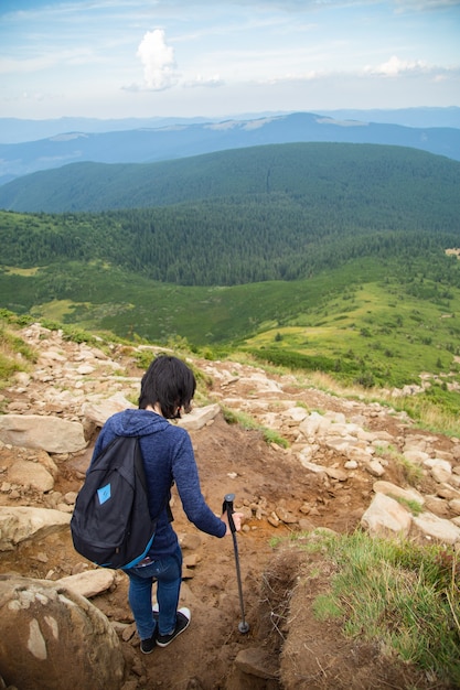 Fille descendre une grande chaîne de montagnes vertes.