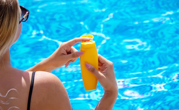 Fille avec un dessin du soleil sur le dos avec de la crème solaire. Détente au bord de la piscine. Mise au point sélective