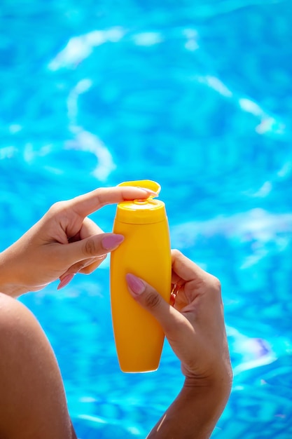 Fille avec un dessin du soleil sur le dos avec de la crème solaire. Détente au bord de la piscine. Mise au point sélective