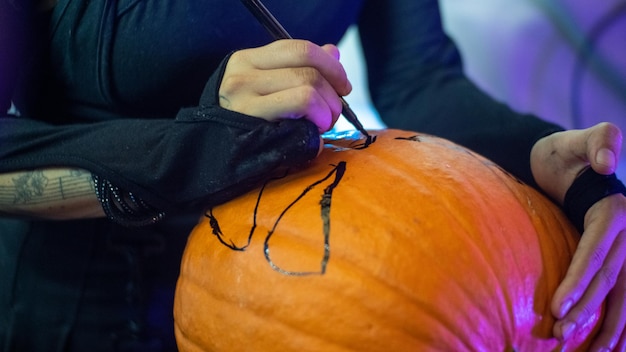 Photo fille dessinant sur une citrouille d'halloween