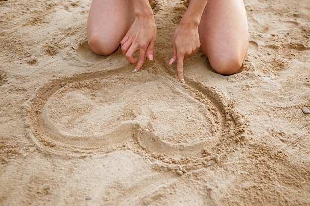 La fille dessine le coeur dans le sable