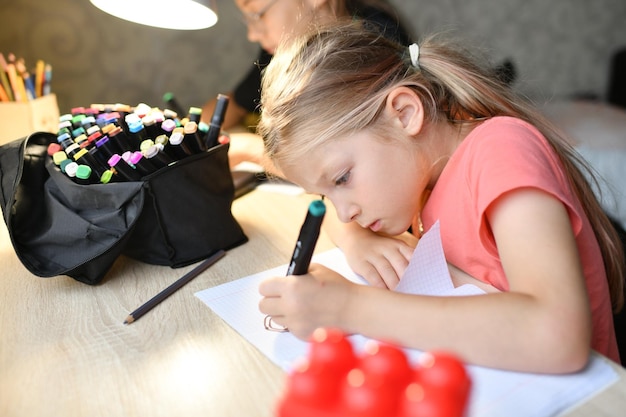 Une fille dessine avec des feutres colorés