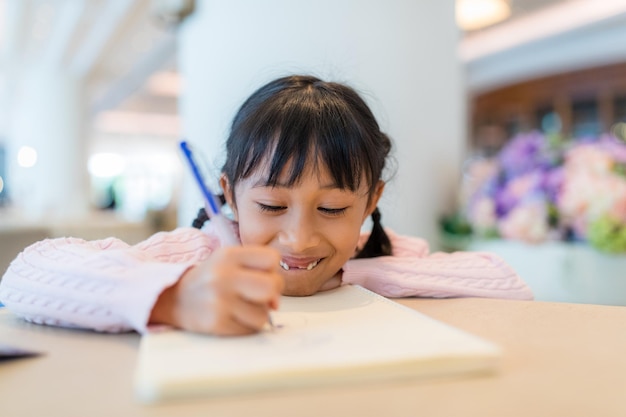 Une fille dessine sur un livre.