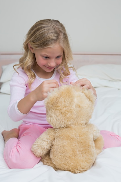 Photo fille détendue assis avec un jouet en peluche dans le lit