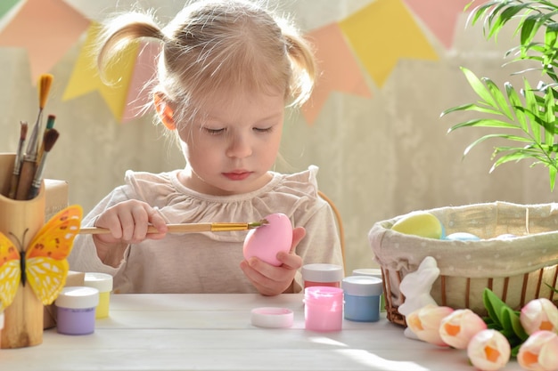 Une fille de deux ans dessine soigneusement des oeufs de Pâques Joyeuses Pâques Faites-le vous-même