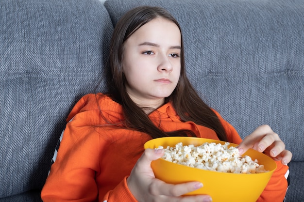 Fille devant la télé et manger du pop corn