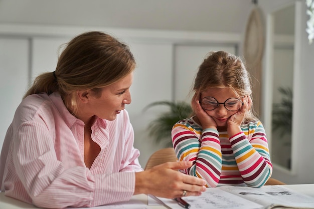 Une fille distraite qui apprend à la maison avec sa mère.