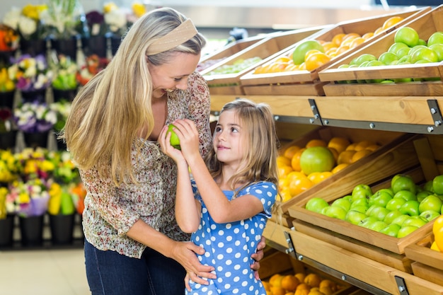 Fille donnant pomme à sa mère dans un supermarché