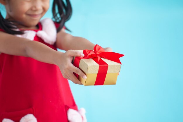 Photo une fille donne une boîte à cadeaux sur un fond bleu