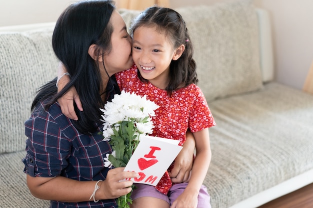 Fille donne la carte de voeux de fête des mères à maman.