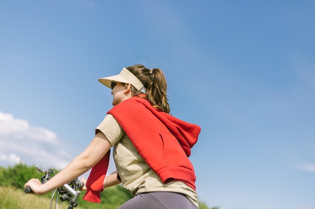 une fille de dos en vélo fait des promenades dans la nature en été