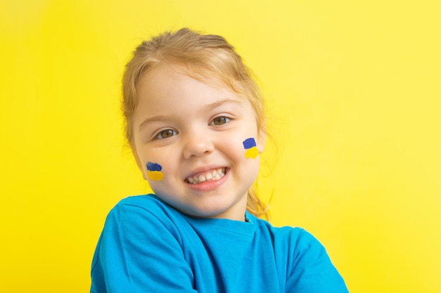 Une fille avec un drapeau ukrainien peint en jaune et bleu sur ses joues