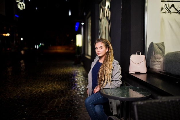 Fille avec des dreadlocks marchant la nuit rue de la ville