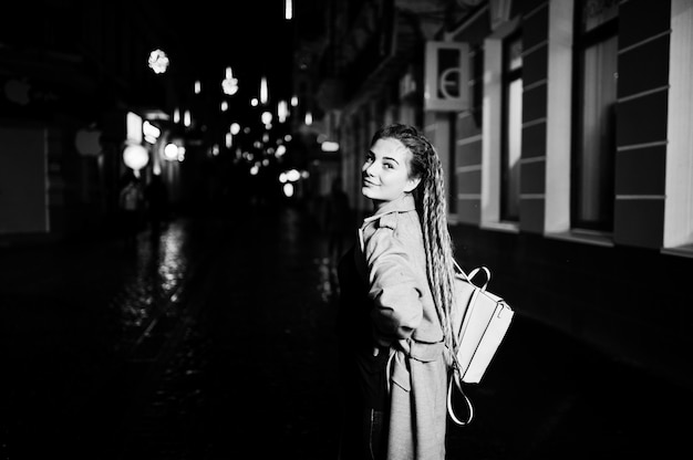 Fille avec des dreadlocks à pied dans la rue de nuit de la ville.