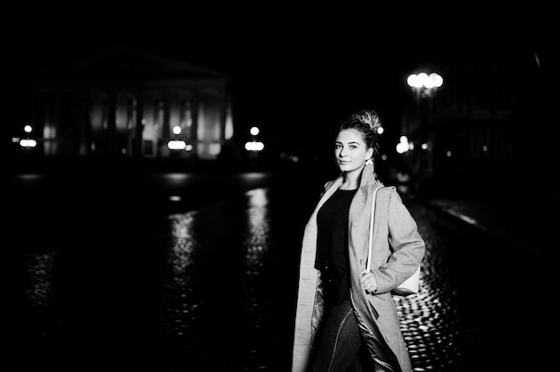 Fille avec des dreadlocks à pied dans la rue de nuit de la ville.