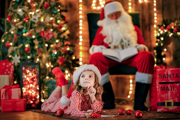 Fille drôle en bonnet de Noel écrit une lettre au père Noël