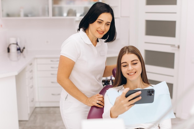 La fille du cabinet dentaire après l'examen prend un selfie avec des dentistes