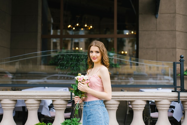 Fille avec du maquillage tenant un bouquet de roses blanches et roses