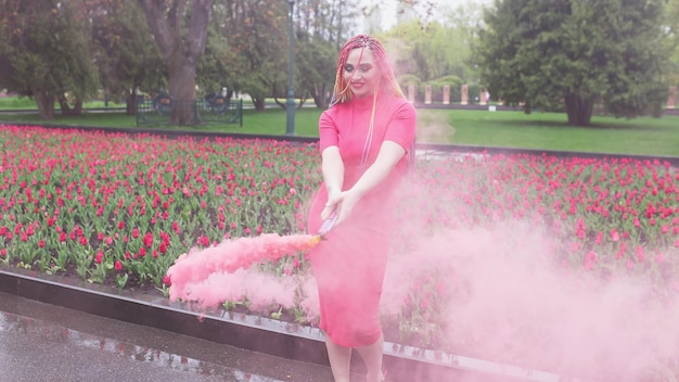 Une fille avec du maquillage avec des tresses arc-en-ciel en robe rouge posant en robe rouge