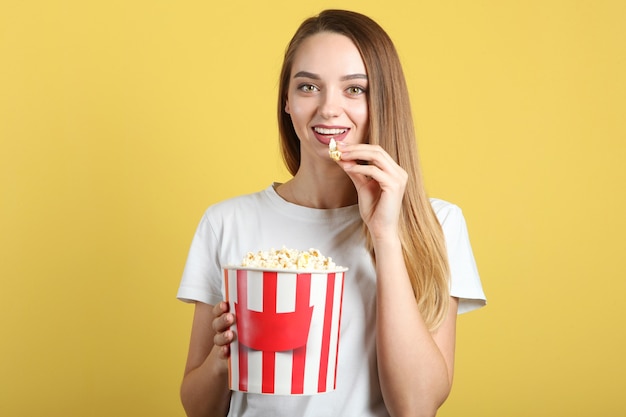 Fille avec du pop-corn sur un fond coloré regarde un film d film