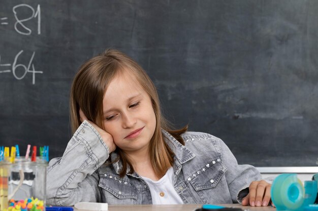 La fille à l'école pense à la façon de résoudre la tâche que le professeur parlait dans la leçon