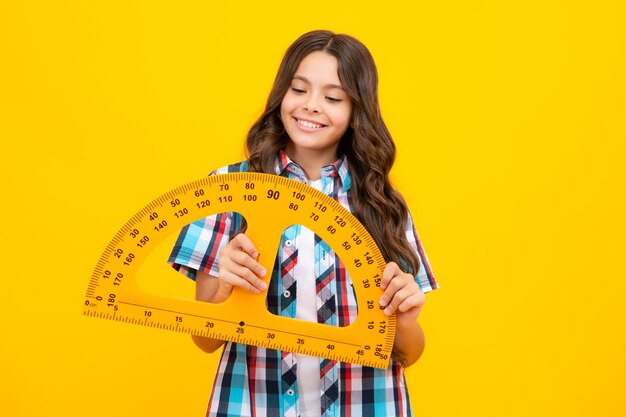 Fille de l'école tenant la mesure pour la leçon de géométrie isolée sur fond jaune Équipement de mesure Mathématiques d'étude des élèves