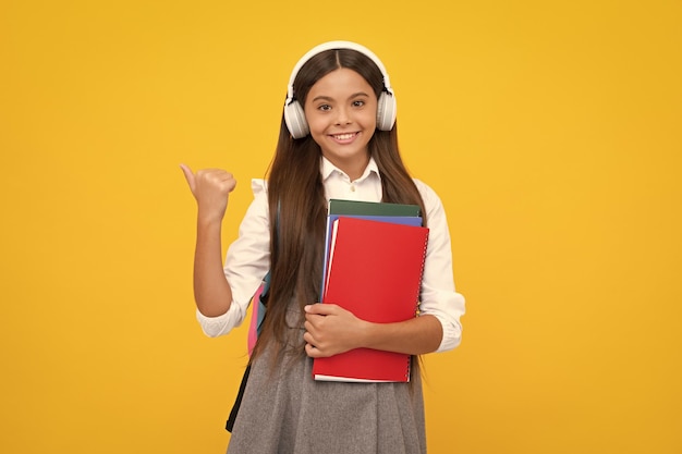 Fille écolière avec casque et livre Bonne fille face à des émotions positives et souriantes