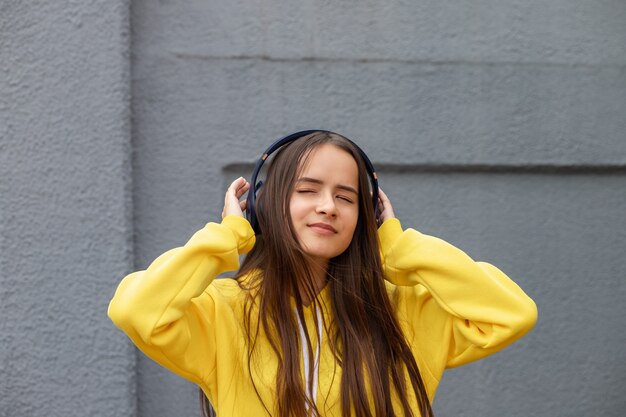 Fille écoutant de la musique avec des écouteurs dans la rue, dansant, profitant de gris