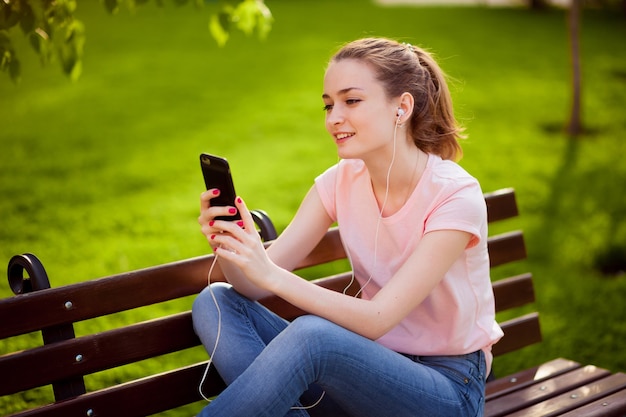 Fille écoutant de la musique avec un téléphone mobile dans le parc