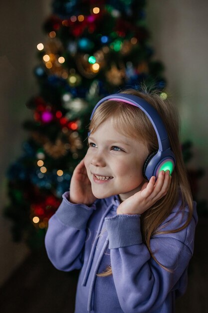 Photo une fille écoute de la musique avec des écouteurs devant un arbre de noël dans un costume violet