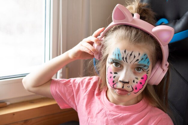 fille écouter de la musique dans un casque rose aquagrim sur le visage