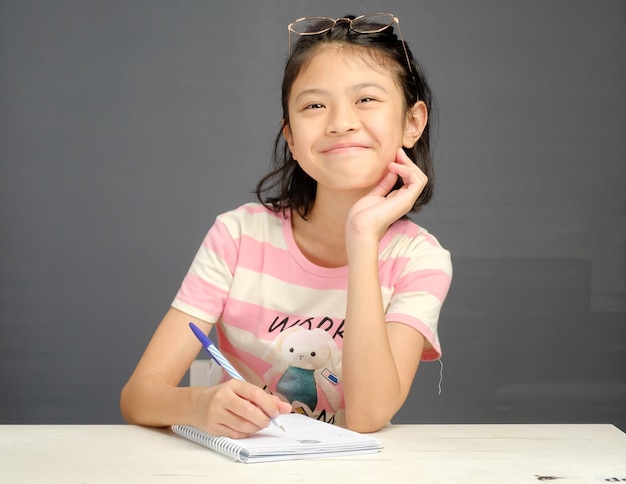 Photo une fille écrit sur un cahier avec une chemise rose et blanche qui dit 