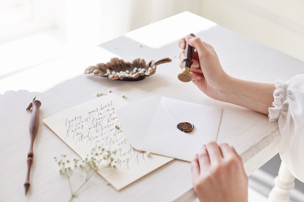 Fille écrit une lettre à son homme bien-aimé assis à la maison