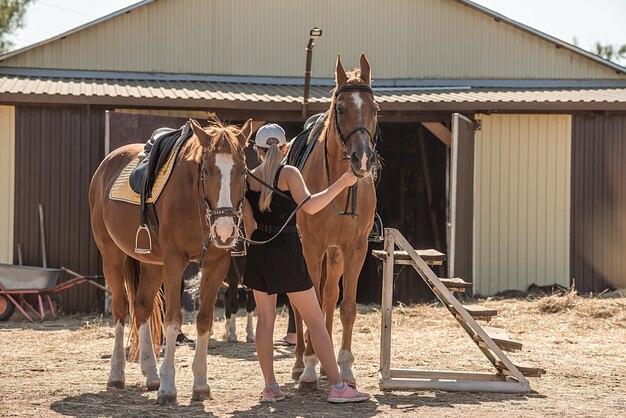 La fille à l'écurie apprend aux enfants à monter. Monter à cheval.