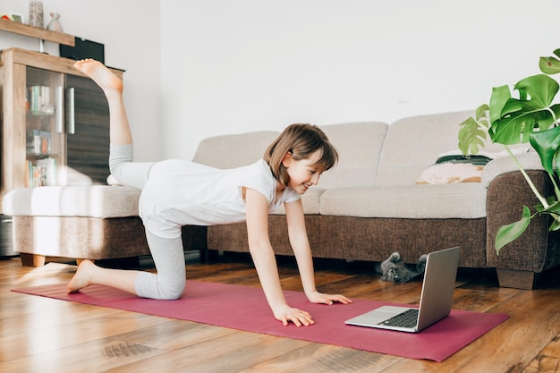 La fille effectue des exercices sportifs à la maison entraînements en ligne mobilité des enfants