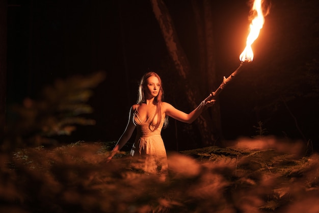 Fille effrayée dans une forêt sombre avec une torche.