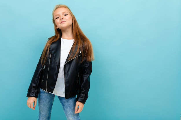 Fille élégante dans un look décontracté avec une veste en cuir, un t-shirt blanc et un jean sur bleu clair