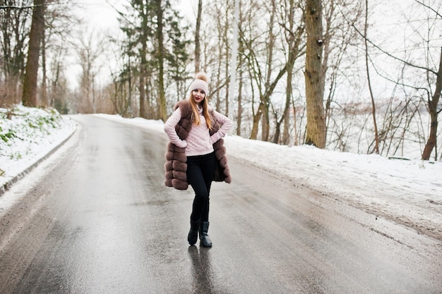 Fille élégante en manteau de fourrure et couvre-chef à la journée d'hiver sur la route